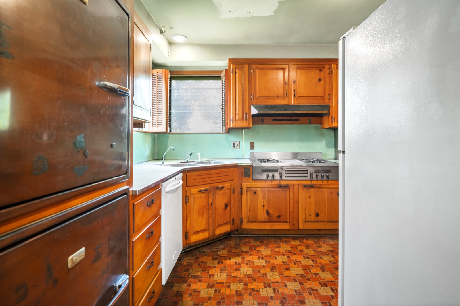 The kitchen, with the built-in Revco refrigerator, Chambers gas cooktop, mint tile backsplash and knotty pine cabinetry